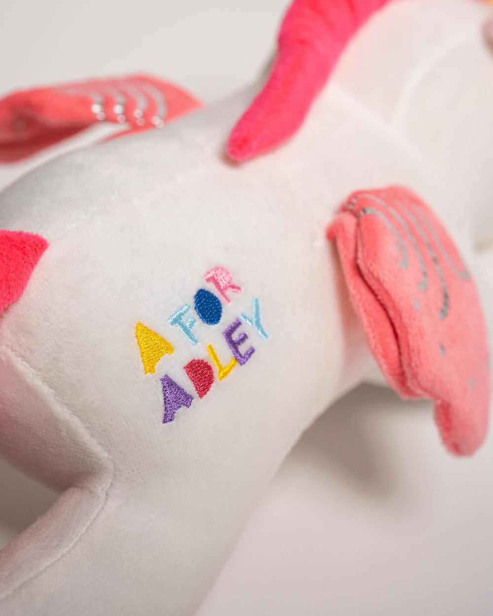 A FOR ADLEY unicorn features silvery wing accents, adding sparkle to playtime.