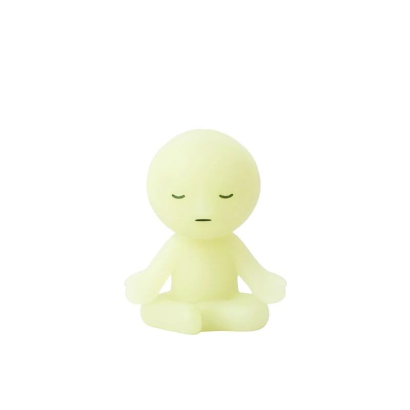 Dreams Smiski Zipperbite Volume 2 in Lotus Pose attached to a bag, offering a subtle, calming glow.