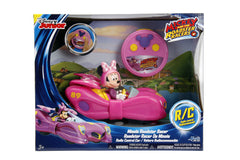 Child racing Minnie Bow RC car on living room floor.