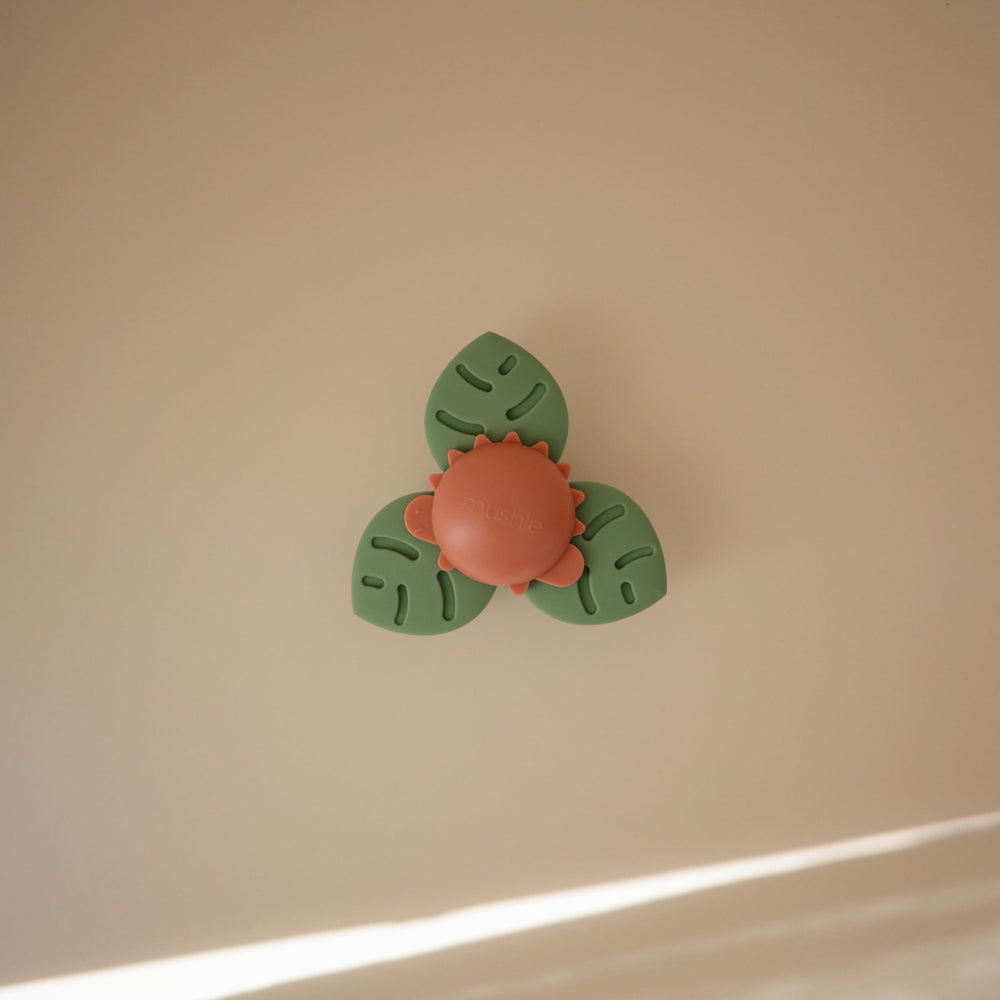 Mushie Dino Suction Spinner Toy attached on highchair for on-the-go play