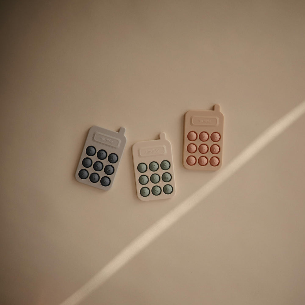 Mushie Phone Press Toy Tradewinds shown in use by a small child.
