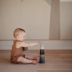 Mushie stacking cups forest baby hand: easy grip cups for tiny hands during stacking play.