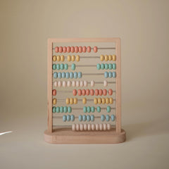 Mushie abacus with muted colors supports calm, focused play.