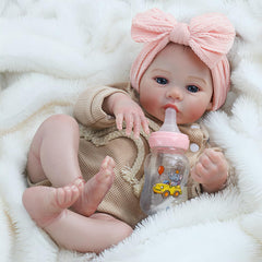 Reborn Baby Dolls Girl wears a tan knit outfit with rainbow stripes and a bow.