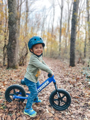 Strider balance bike 12-inch blue safety pad cushions bumps on rides.