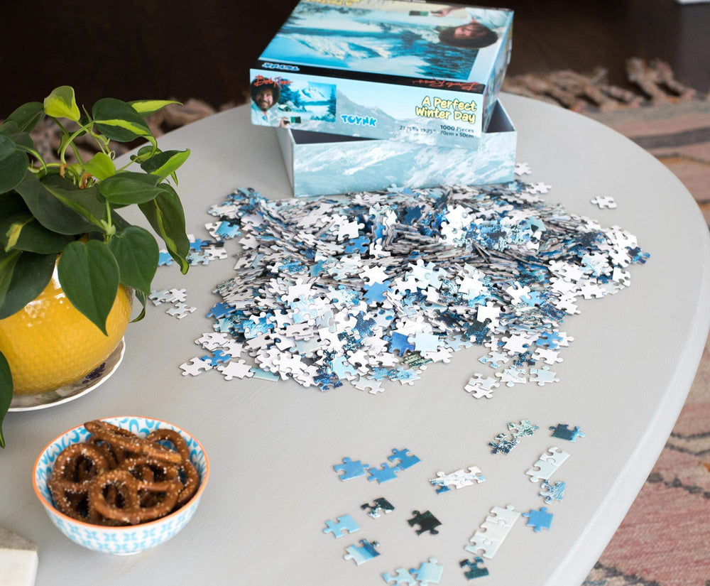 Toynk Bob Ross puzzle shows a log cabin amid a winter forest for solo focus.