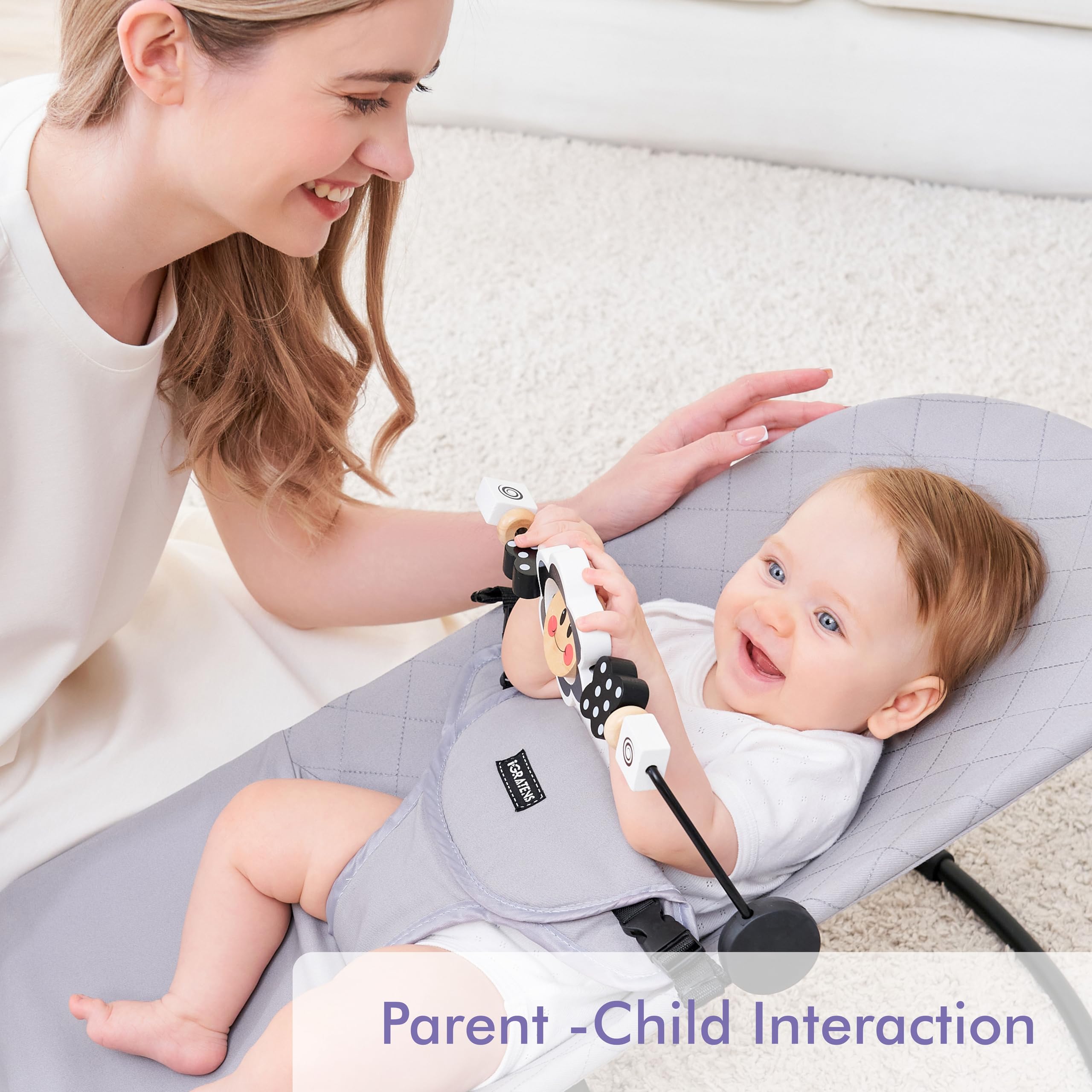 Baby using iGRATENS toy bar attached to a bouncer for engaged play