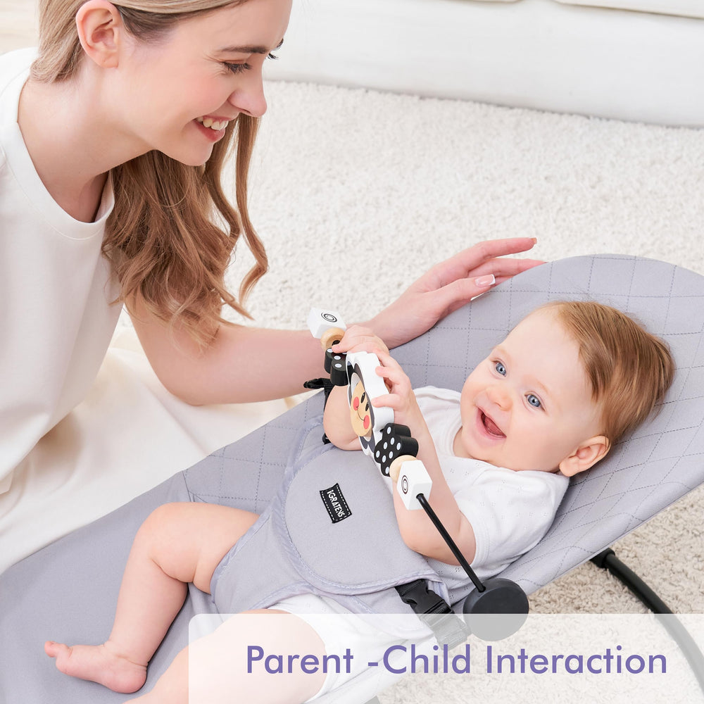 Baby using iGRATENS toy bar attached to a bouncer for engaged play