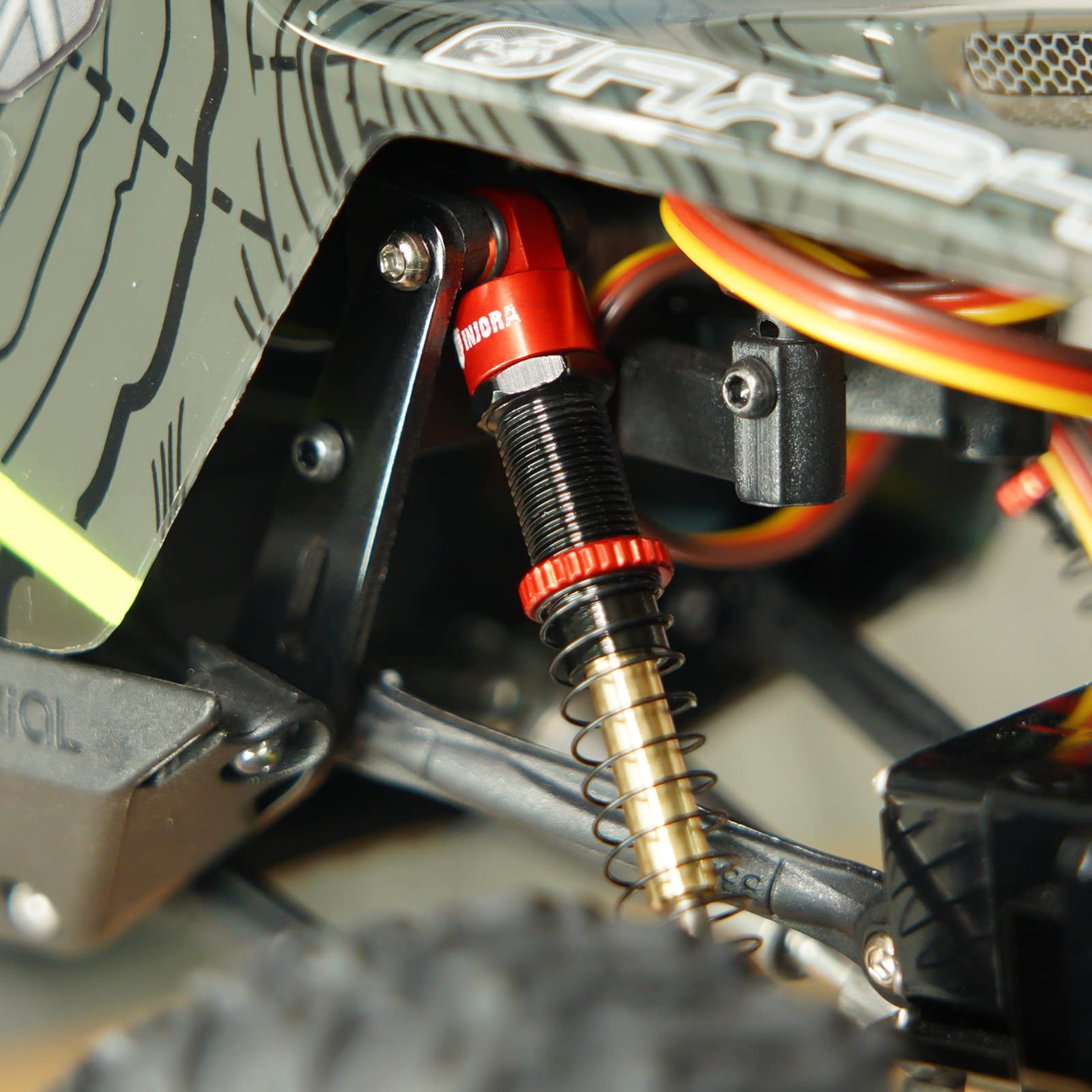 INJORA RC crawler AX24 in action with red shocks during a test run.