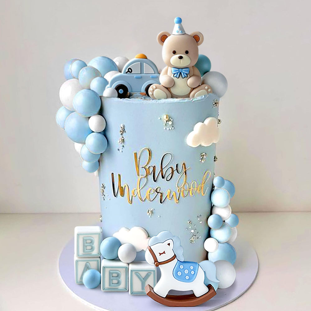 JeVenis blue bear topper with gold balls creates a photo-worthy centerpiece.