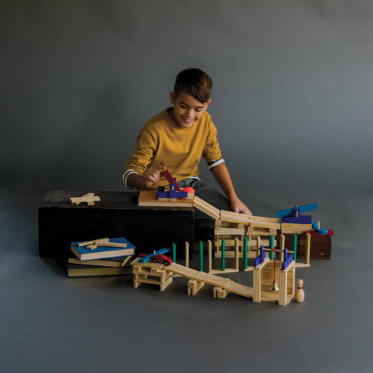 MindWare KEVA Contraptions marble maze demonstrates simple physics with ramps and tunnels.