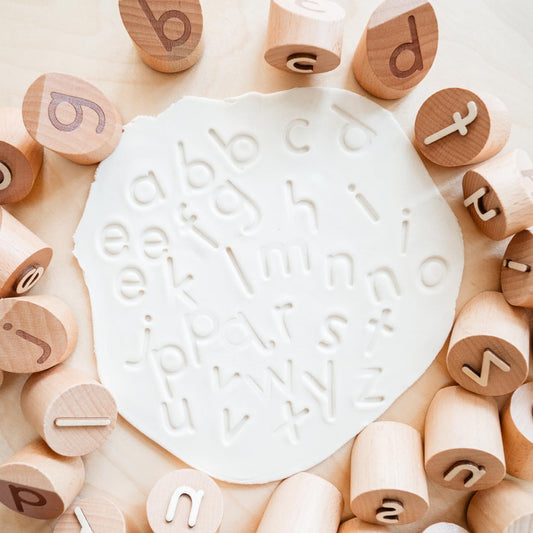 Montessori & Me Alphabet Stamps in wood with easy-to-hold handles promote precise stamping.