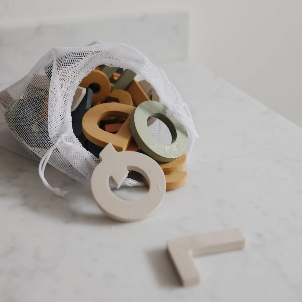 Mushie bath time foam collection on tub: soft textures invite safe, imaginative play.