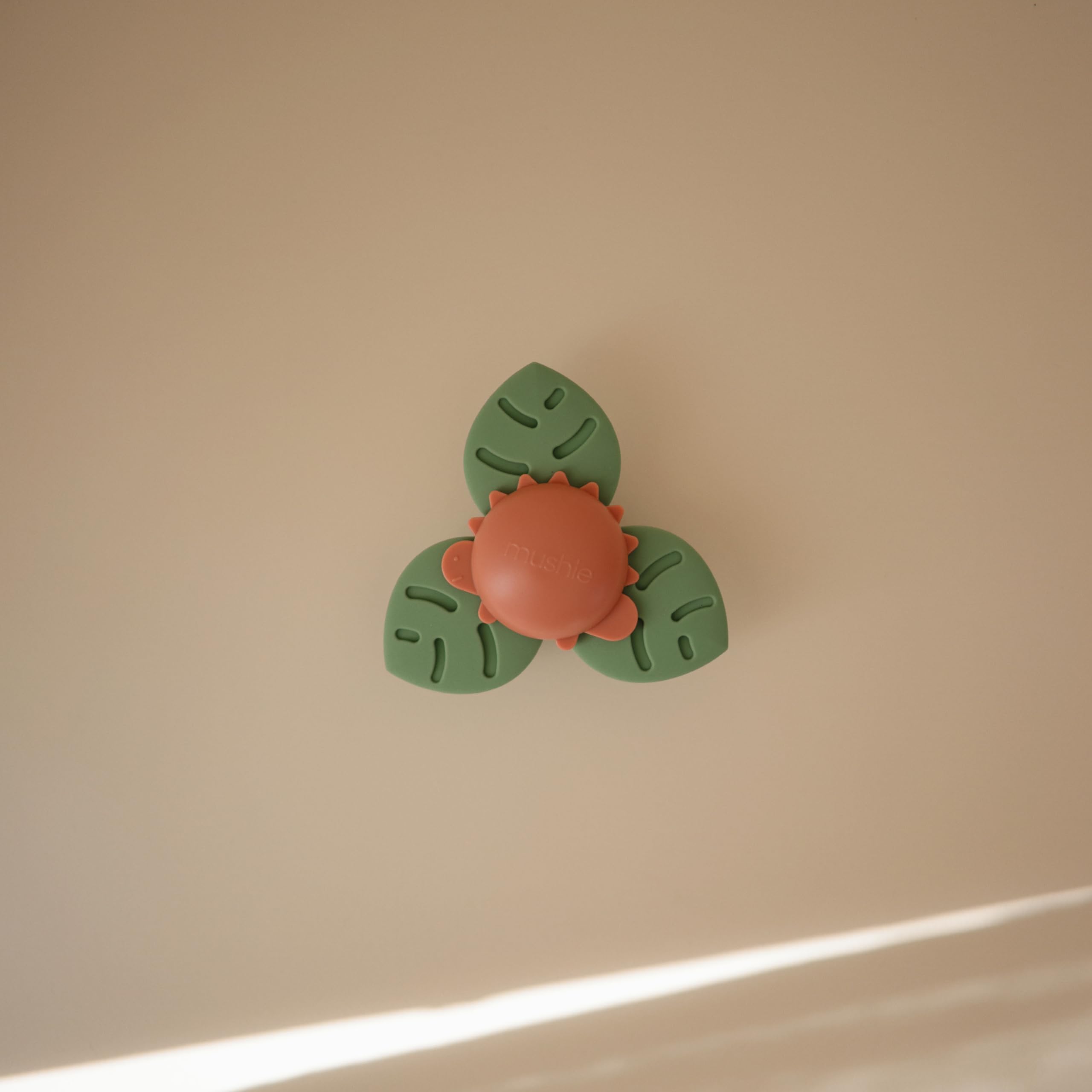 Mushie Dino Suction Spinner Toy attached on highchair for on-the-go play