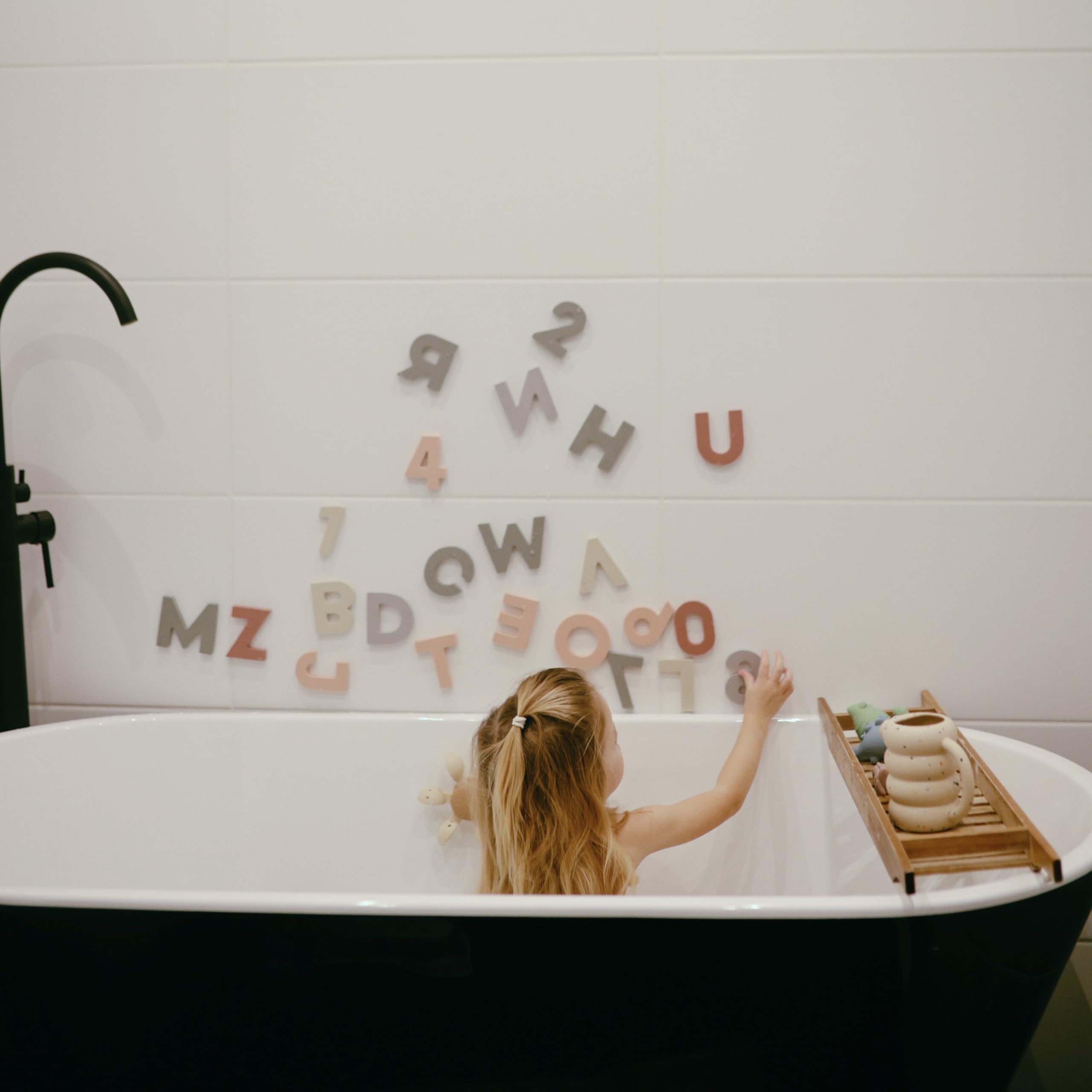 Mushie floating foam shapes on water: colorful pieces cling to tub walls for engaging play.
