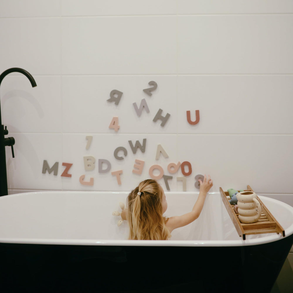 Mushie letters and numbers foam sticks to tub surfaces for interactive sorting.