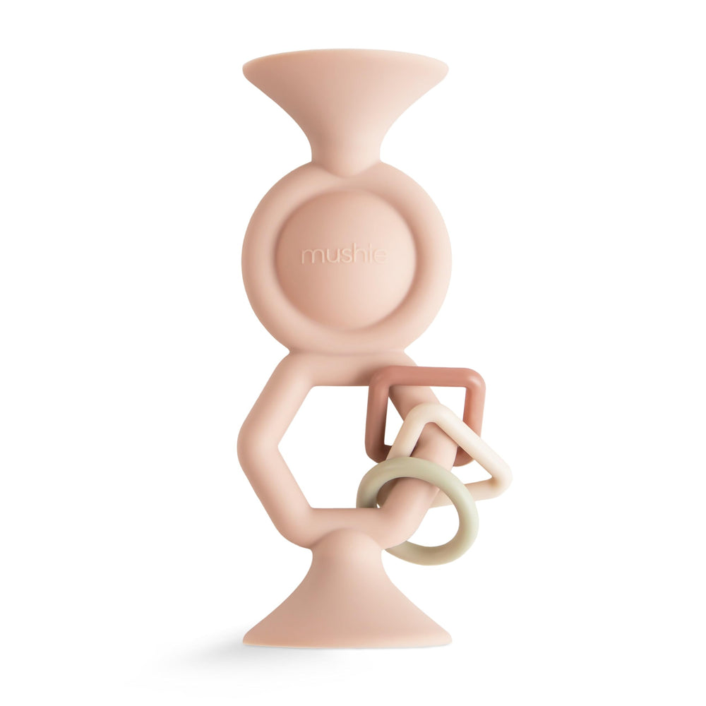 Mushie HexaPop suction toy on a smooth surface, easy reach for little hands.