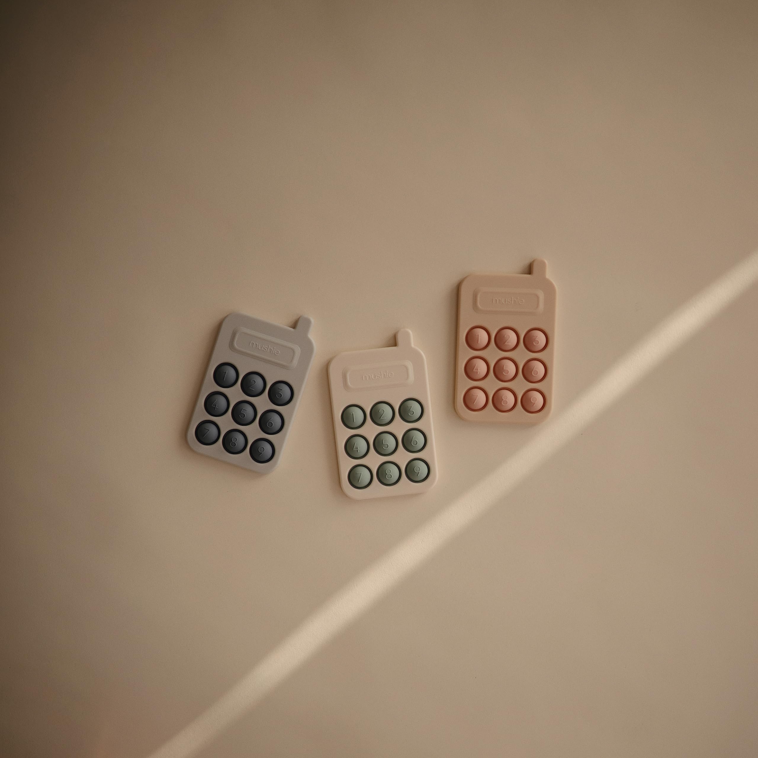 Mushie Phone Press Toy Tradewinds shown in use by a small child.