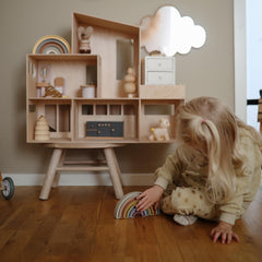 Mushie rainbow stacker in use, child stacks blocks to explore balance.