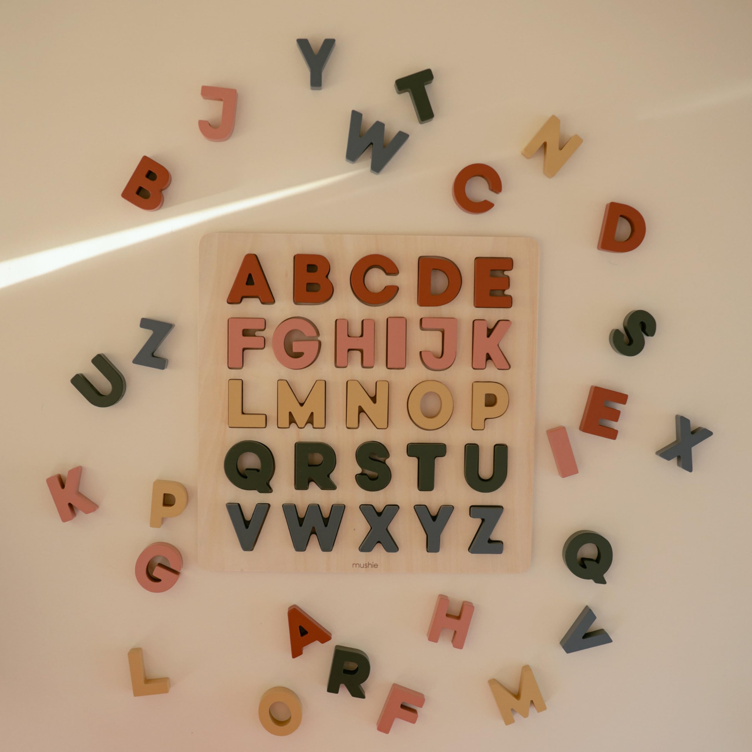 Mushie wooden alphabet puzzle close-up edges show safe, smooth pieces.