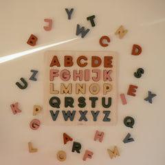 Mushie wooden alphabet puzzle close-up edges show safe, smooth pieces.