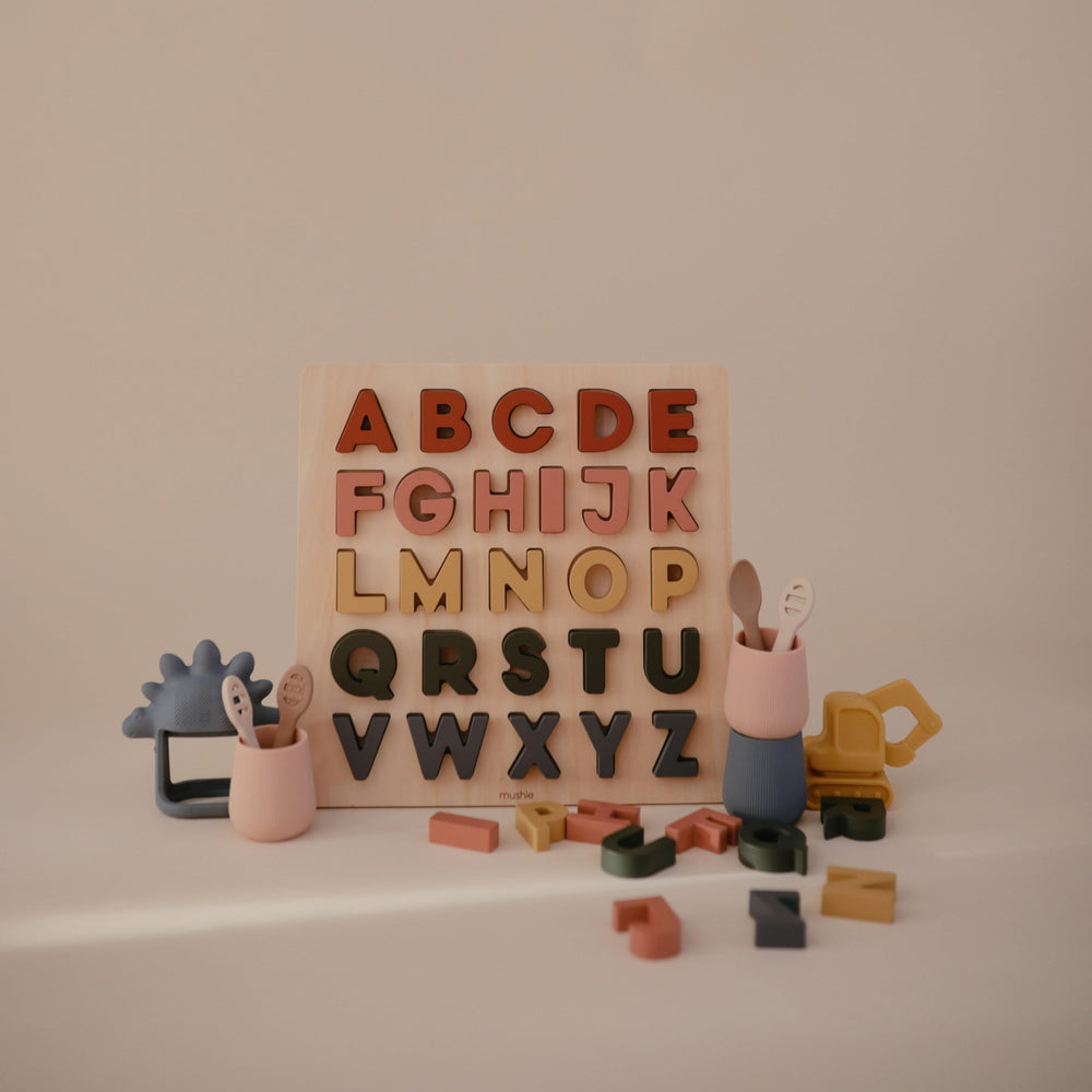 Mushie wooden alphabet puzzle packaging and storage-ready design.