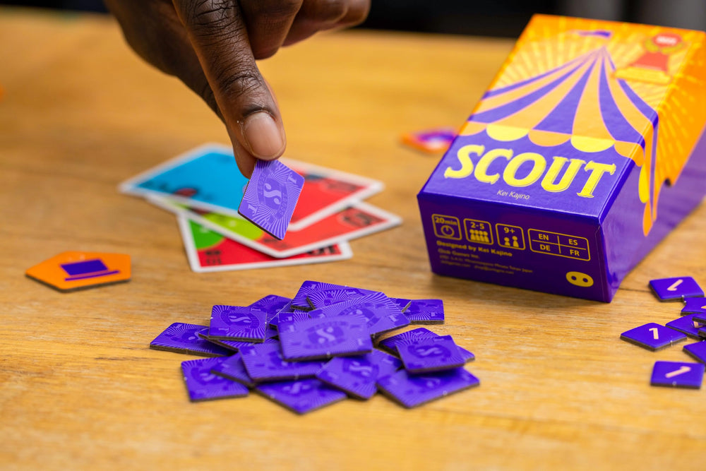 Oink Games Scout next to a smartphone for scale, emphasizing pocket portability