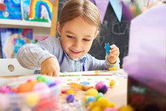 Olly Kids crafting indoors with glue, stickers, and color supplies.