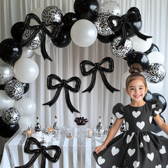 PartyXpress black-white theme bow balloons pair with shimmer garlands for elegant setups.