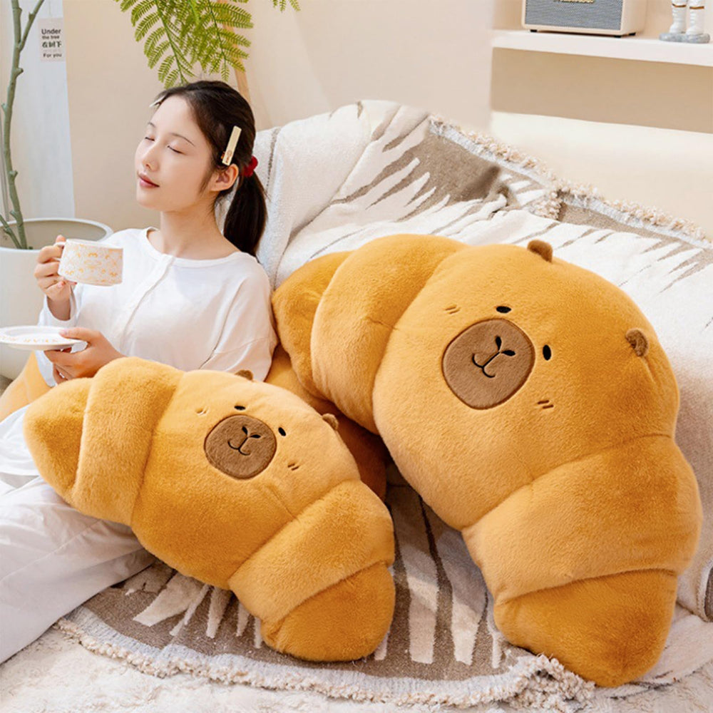 PEACH CAT croissant capybara plush, backrest on sofa, supports comfortable seating.