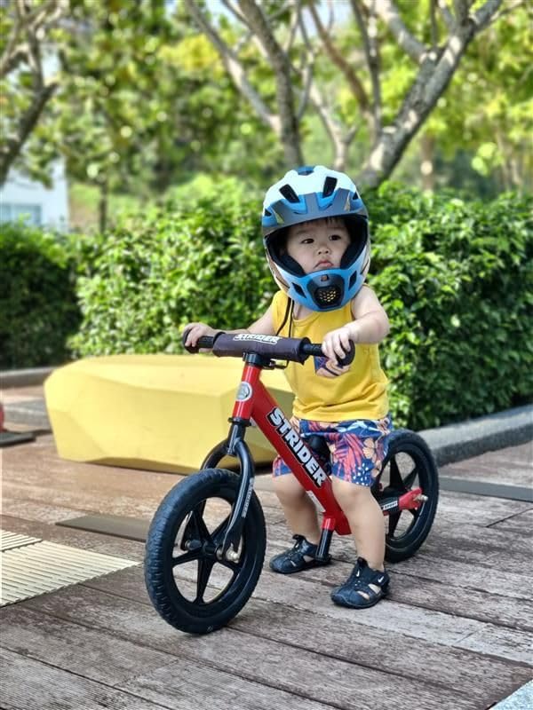 Strider red kid riding action outdoors showing first balance skills.
