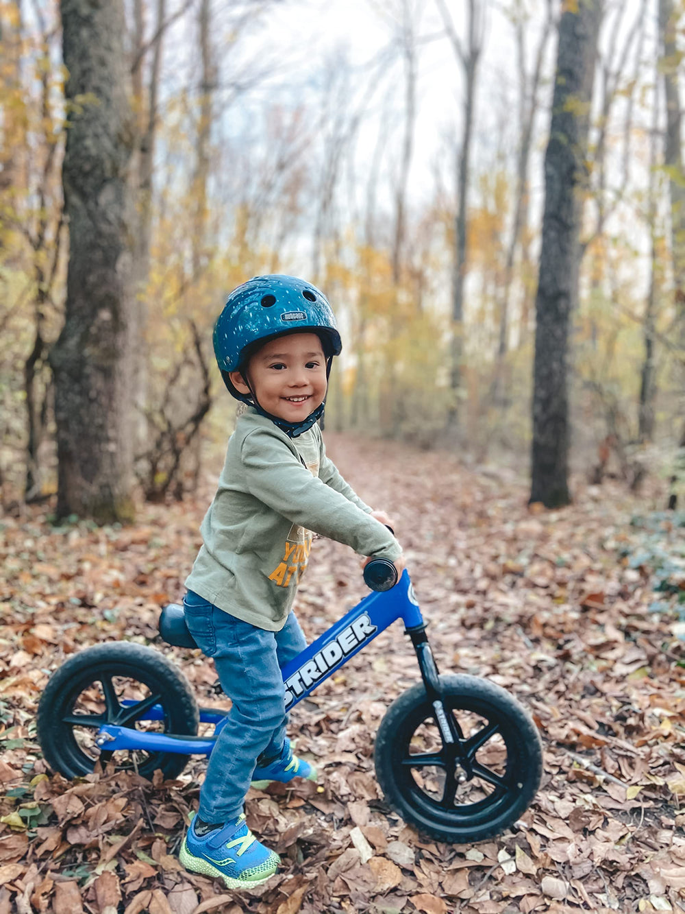 Strider balance bike 12-inch blue safety pad cushions bumps on rides.