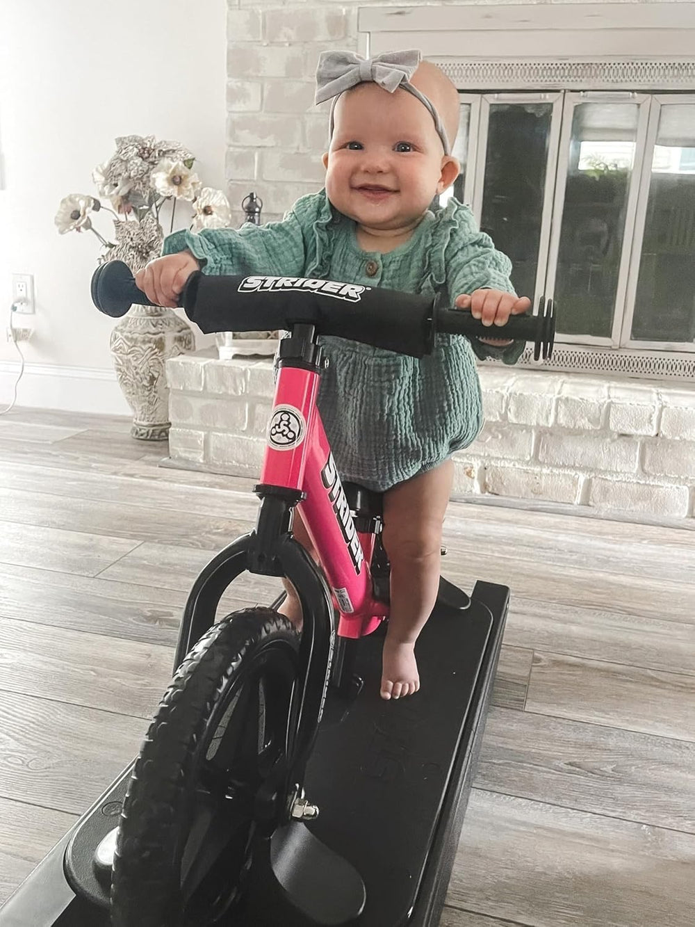 Child practicing balance with Strider bike and rocking base in a teaching scene.