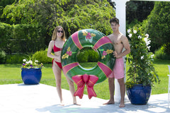 Swimline Christmas Wreath Ring being lounged under the sun for cooling relaxation.