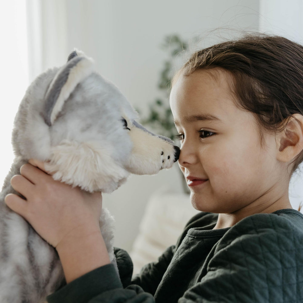 The Petting Zoo wolf plush in a child’s arms inviting imaginative playtime.