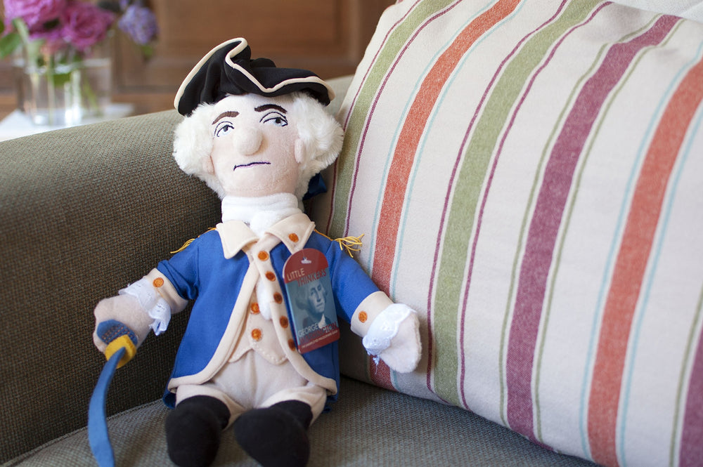 The Unemployed Philosophers Guild George Washington doll seated on a base with pellets for stable display.