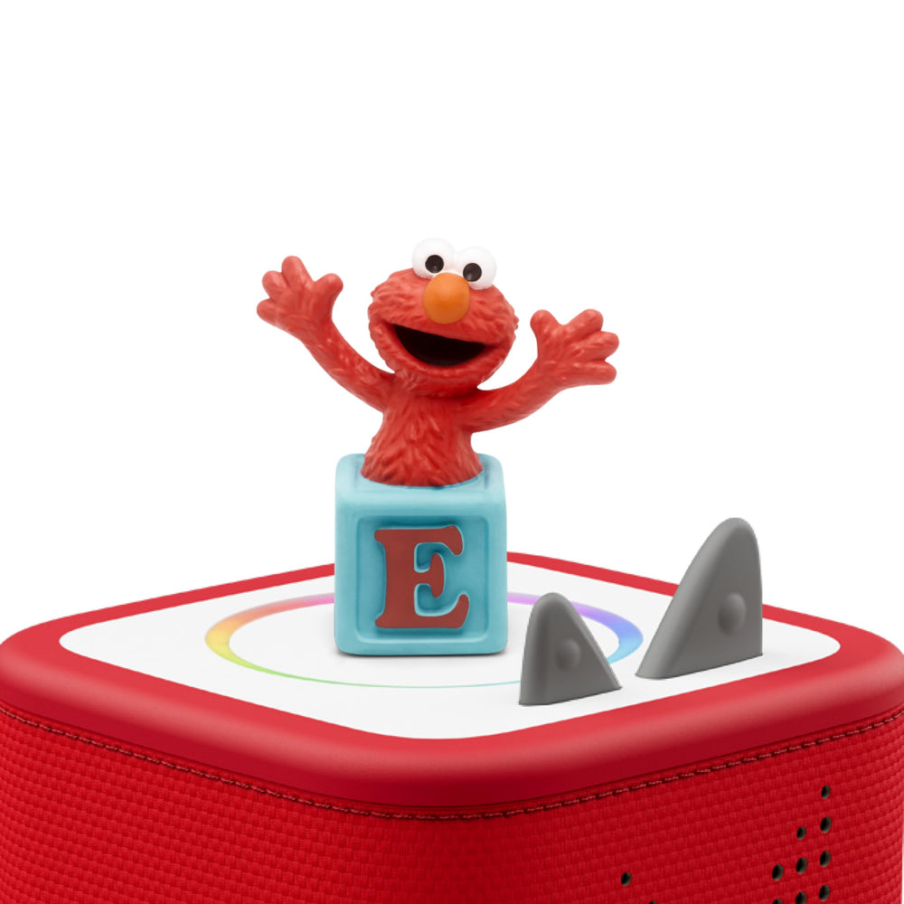 Elmo sits on a Toniebox, inviting music and storytelling.