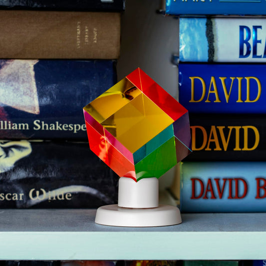 Close-up of cyan-yellow-magenta prism reveals smooth acrylic edges and light refractions.